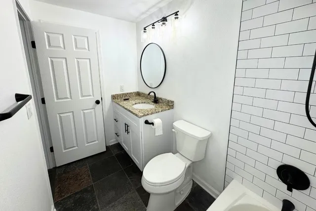a white toilet sitting next to a bathroom sink and a mirror