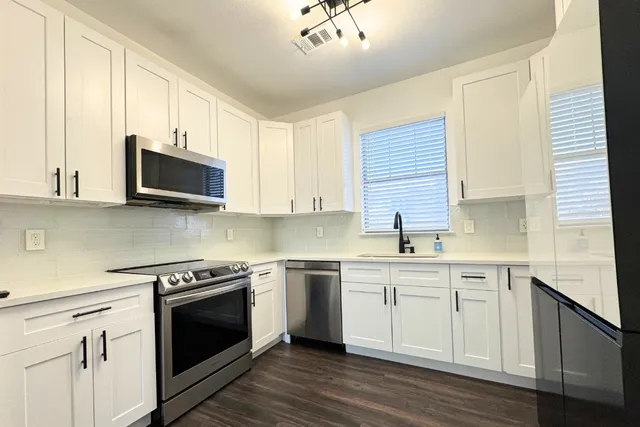 a kitchen with cabinets stainless steel appliances and wooden floor