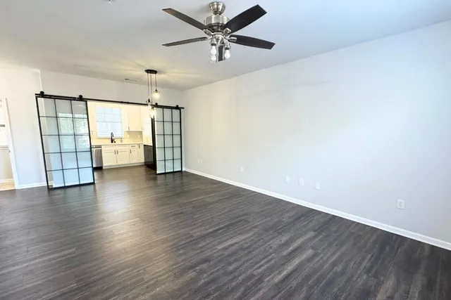 a view of an empty room with window and wooden floor