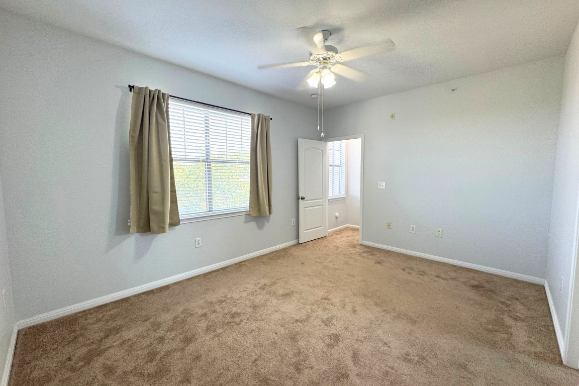 11203 Ranch Road 2222, Unit 2203 Austin, TX 78730 - Photo 23 of 34 an empty room with windows and chandelier fan