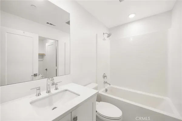 a bathroom with a bathtub shower sink vanity mirror and toilet