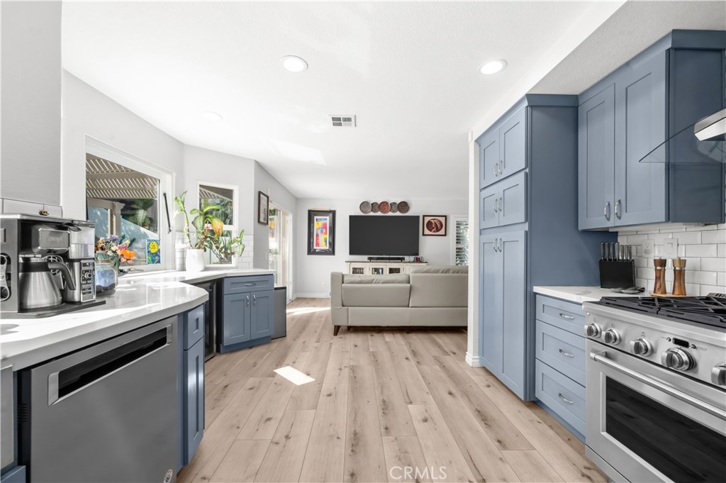 19465 Kinnow Lane Riverside, CA 92508 - Photo 16 of 61 a kitchen with stainless steel appliances a stove a sink dishwasher a refrigerator white cabinets and wooden floor