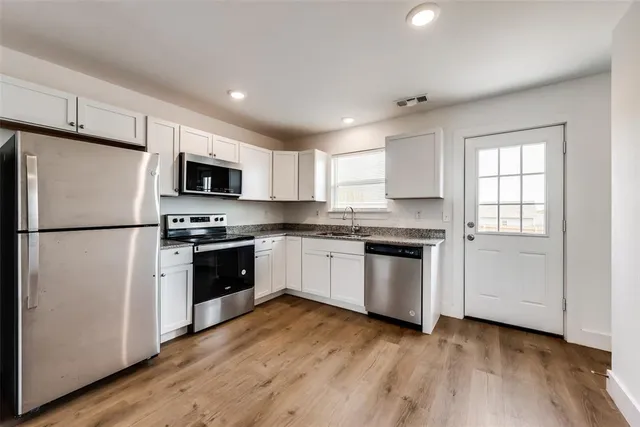 a kitchen with granite countertop a refrigerator stove a sink and dishwasher with wooden floors