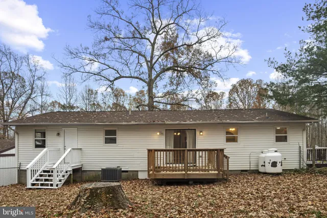 a backyard of a house with large trees and wooden fence