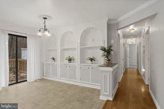 a hallway with white cabinets and chandelier