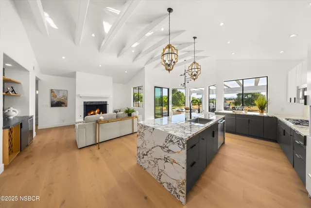 a large white kitchen with a large island in the center