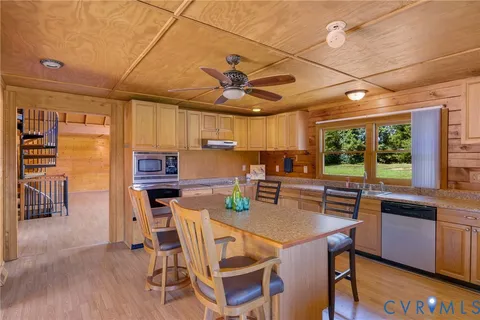 a kitchen with stainless steel appliances kitchen island granite countertop a table chairs in it and a wooden floors