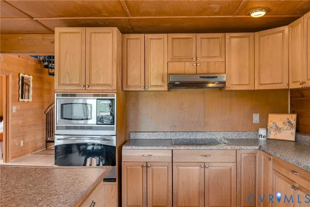 a kitchen with stainless steel appliances granite countertop a refrigerator a sink dishwasher a stove and a dining table with wooden floor