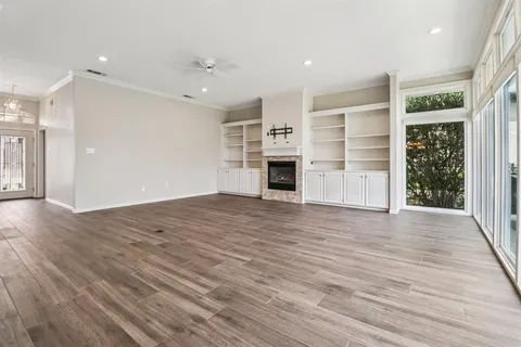 an empty room with wooden floor fridge and windows