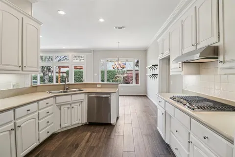 a kitchen with white cabinets a sink dishwasher and a stove with wooden floor