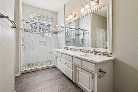 a bathroom with a double vanity sink mirror and shower