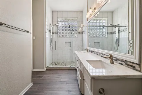 a bathroom with a granite countertop sink a mirror and a shower