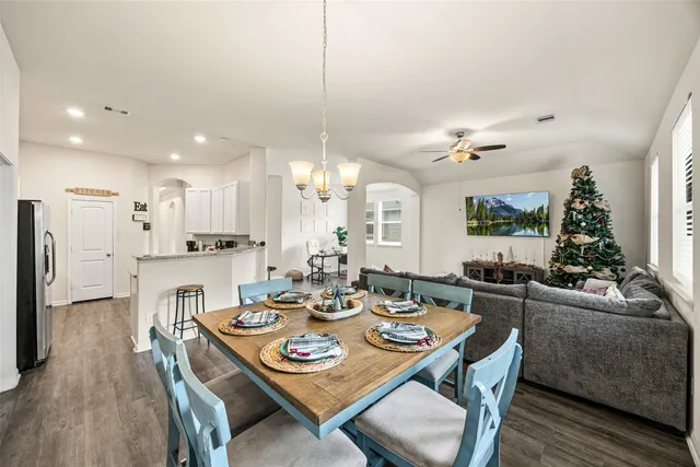 a view of a dining room and livingroom with furniture wooden floor a rug a fireplace and a chandelier