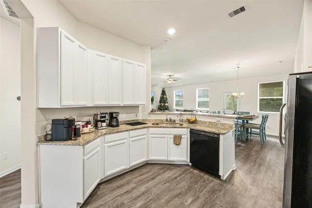 a kitchen with white cabinets sink and dining table chair