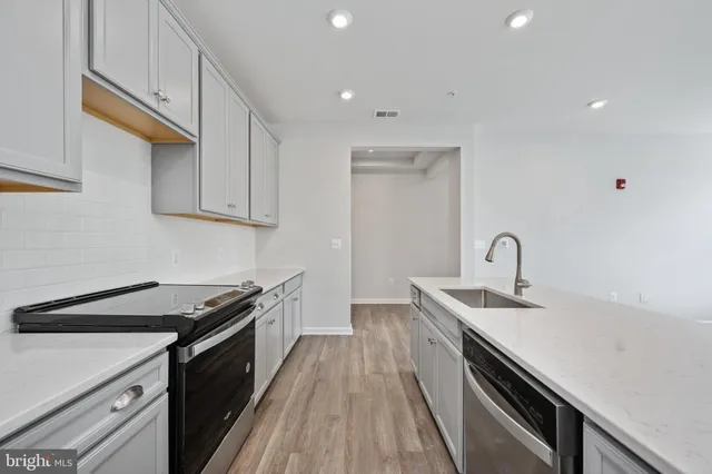 a kitchen with a sink a stove a refrigerator and white cabinets