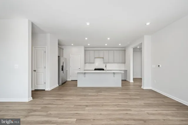 a kitchen with stainless steel appliances granite countertop a stove top oven a refrigerator and white cabinets with wooden floor