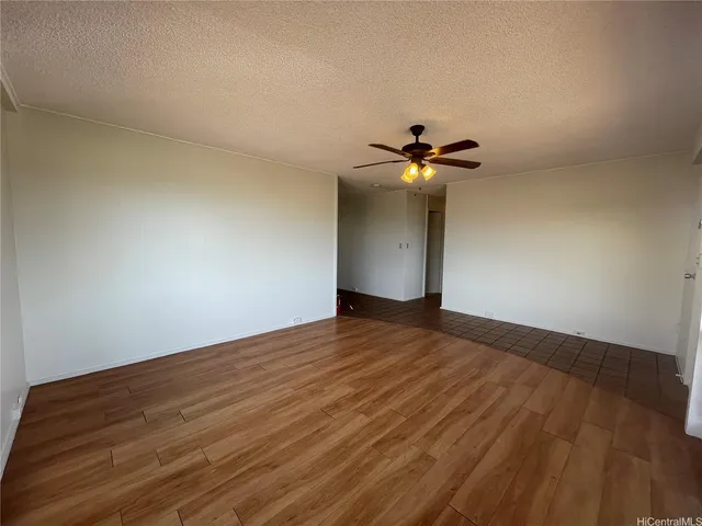 a view of a room with wooden floor and a ceiling fan