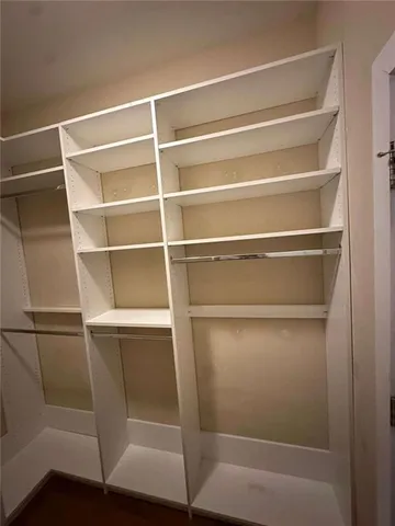 a walk in closet with wooden floor