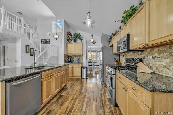 a kitchen with stainless steel appliances granite countertop a stove a sink and a refrigerator