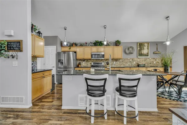 a kitchen with stainless steel appliances kitchen island granite countertop a table and chairs in it