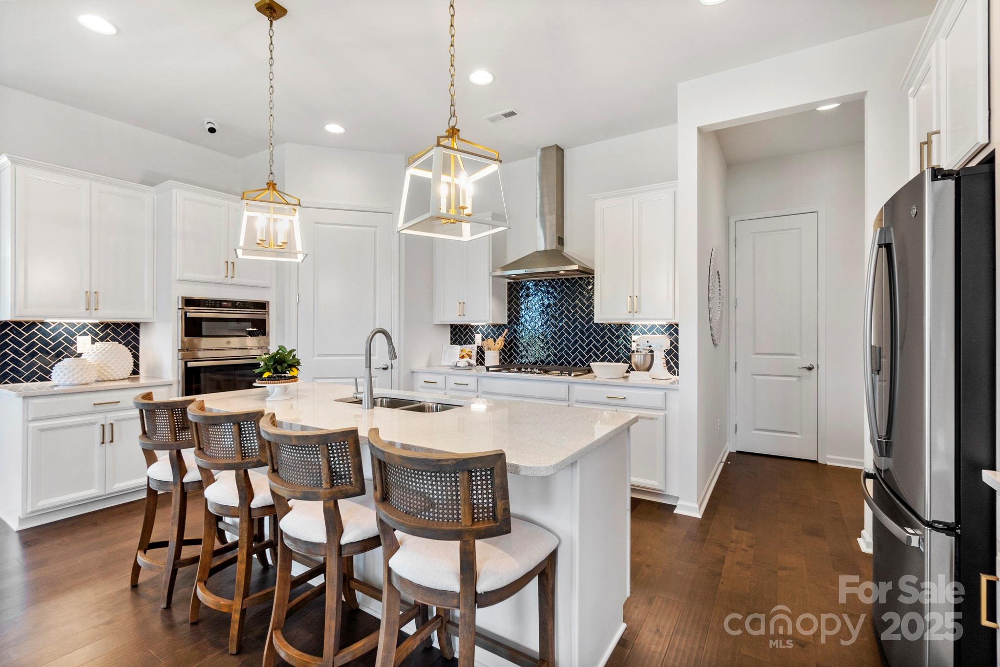 a kitchen with stainless steel appliances kitchen island granite countertop a table chairs and a refrigerator