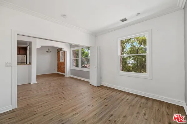 an empty room with wooden floor and windows