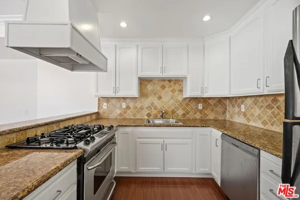 a kitchen with granite countertop white cabinets and stainless steel appliances