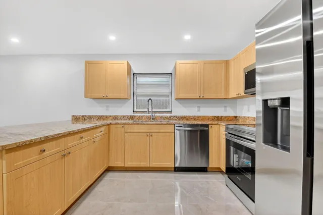 a kitchen with stainless steel appliances granite countertop white cabinets a sink and a microwave