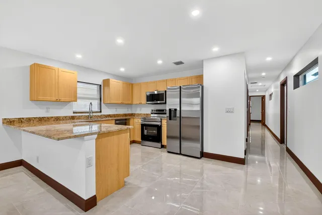 a kitchen with stainless steel appliances granite countertop a refrigerator a stove top oven a sink and dishwasher