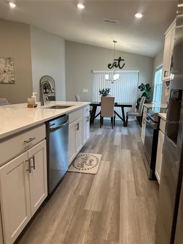 a very nice looking kitchen with granite countertop a sink dishwasher a stove and white cabinets with wooden floor