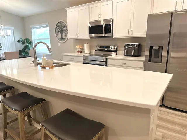 a kitchen with stainless steel appliances granite countertop a sink a stove and a refrigerator with wooden floor