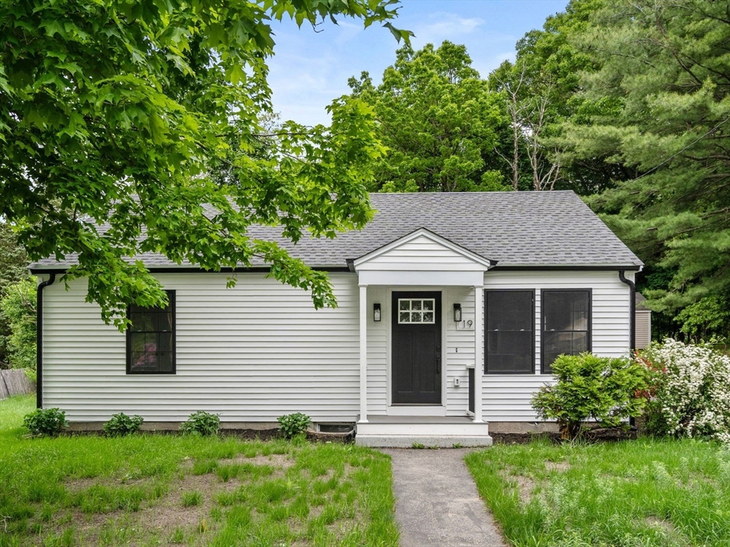 a view of a white house with a small yard and a large tree