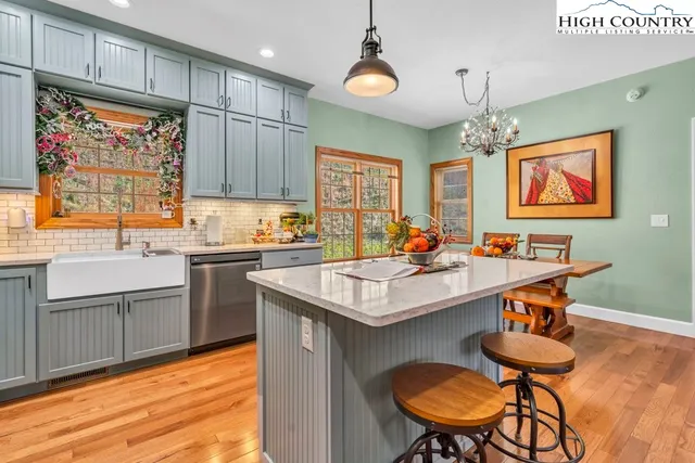 a kitchen with stainless steel appliances granite countertop a sink a stove and chairs with wooden floor