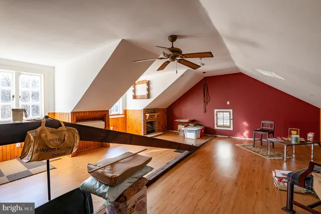 a view of an empty room with wooden floor fireplace and a window