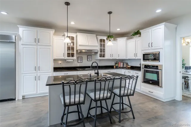 a kitchen with stainless steel appliances kitchen island a table chairs in it and wooden floors