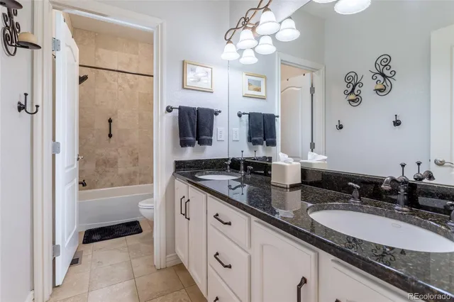 a bathroom with a granite countertop double vanity sink a mirror a bathtub and shower
