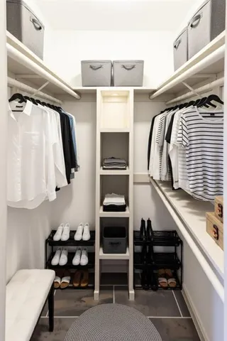 a view of walk in closet with clothes and shoes