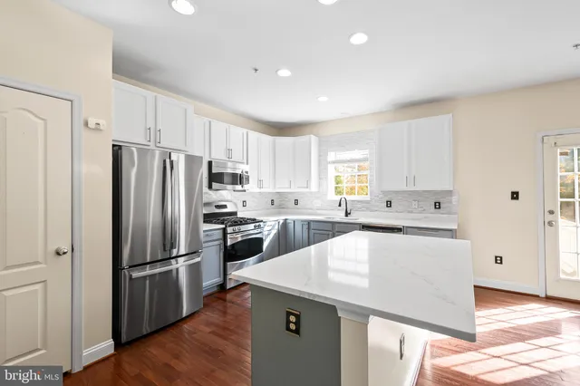 a kitchen with stainless steel appliances a refrigerator sink and white cabinets