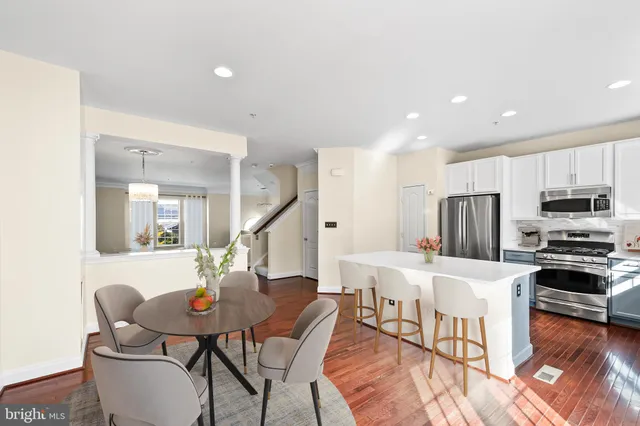 a living room with stainless steel appliances kitchen island granite countertop a dining table chairs refrigerator and sink