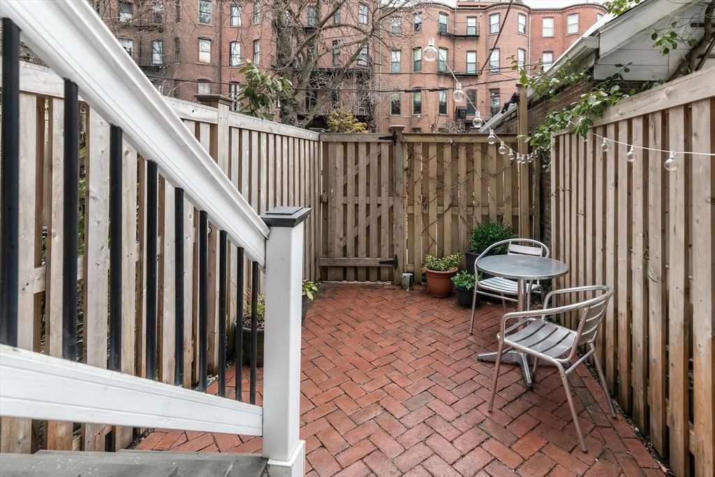 23 Braddock Park, Unit 2 Boston, MA 02116 - Photo 20 of 22 a backyard of a house with table chairs and iron fence