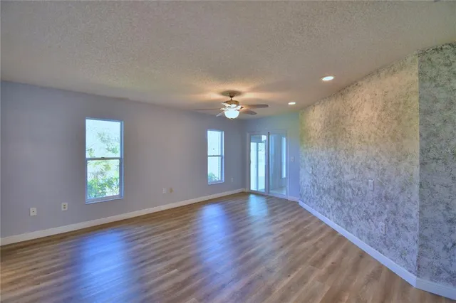 an empty room with windows and ceiling fan