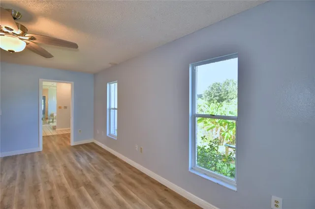 an empty room with windows and fan