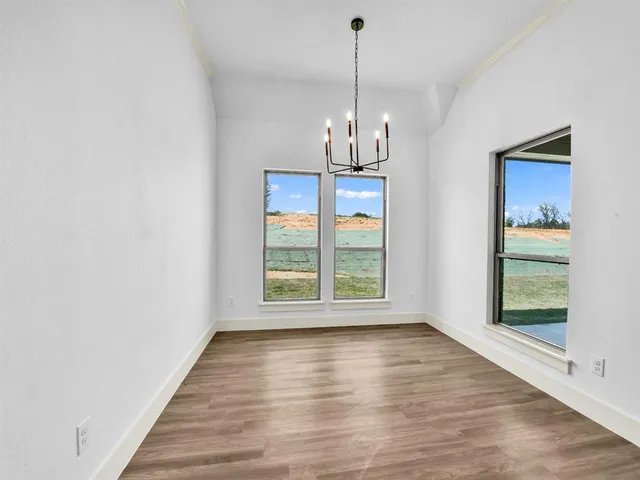 a view of empty room with wooden floor and window