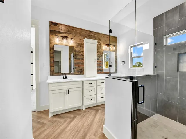 a spacious bathroom with a double vanity sink a large mirror a shower and a bathtub