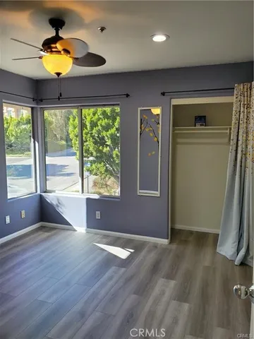 a view of empty room with wooden floor and fan