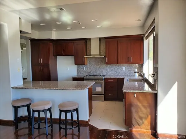 a kitchen with stainless steel appliances granite countertop a table chairs sink and cabinets