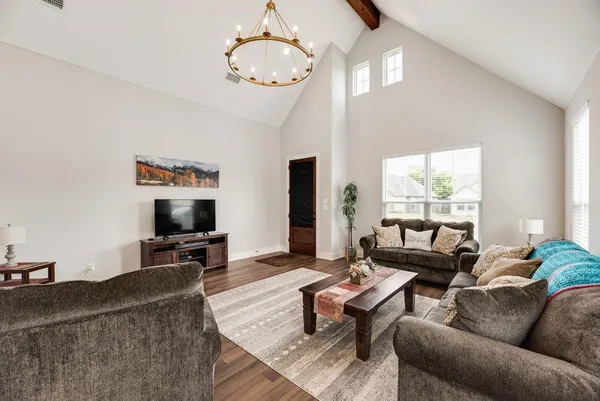 a living room with furniture a chandelier and a flat screen tv