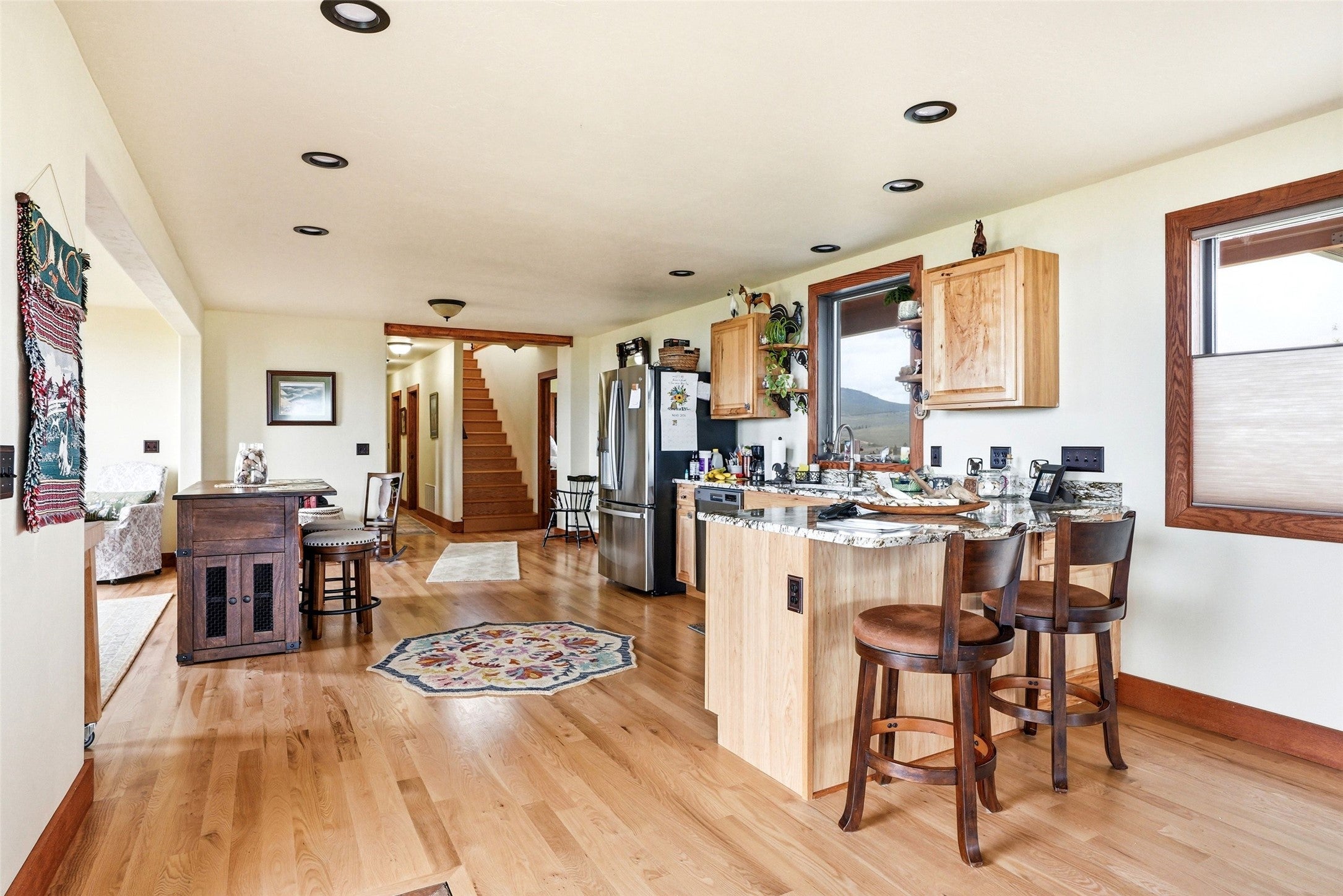 679 Hidden Valley Road North Florence, MT 59833 - Photo 21 of 85 Open-concept living area featuring wood-finish flooring throughout, a kitchen island with seating, recessed ceiling lighting, and wood-framed windows