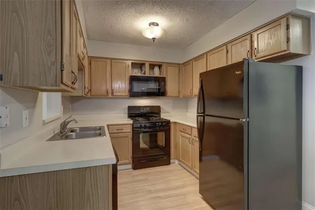 a kitchen with stainless steel appliances granite countertop a refrigerator stove and sink