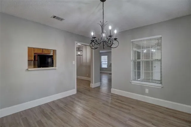a view of a room with wooden floor chandelier and windows